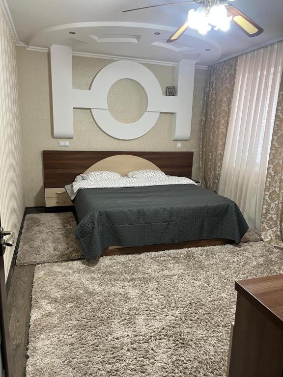 a bedroom with a bed with a large t sign on the wall at Spacious Modern Apartment mins drive to City Center in Chişinău