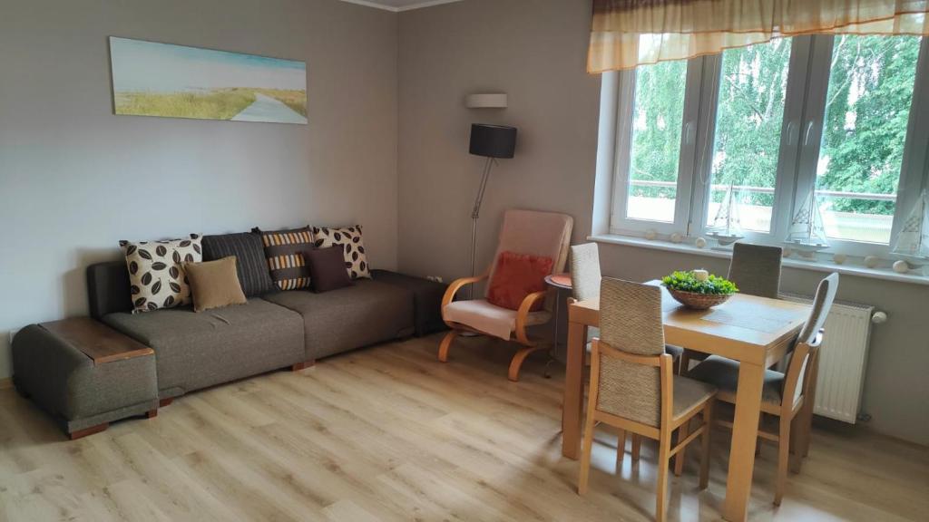 un soggiorno con un divano, un tavolo e delle sedie di CHILLIapartamenty - FREDRY a Kołobrzeg