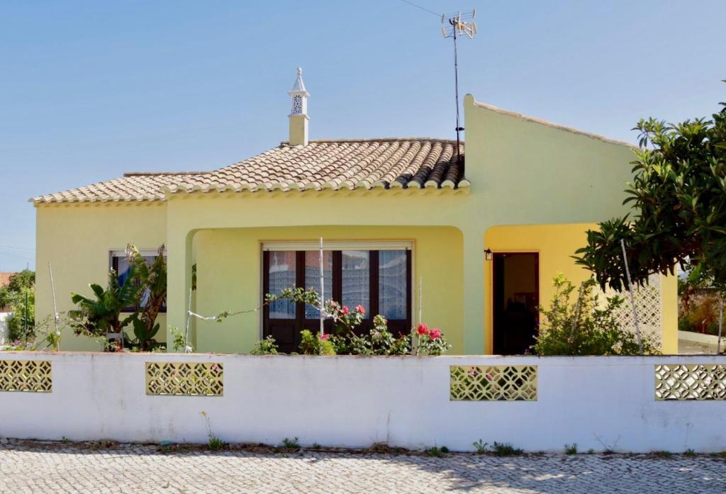una casa gialla con una recinzione bianca di Casa do Afonso a Sagres