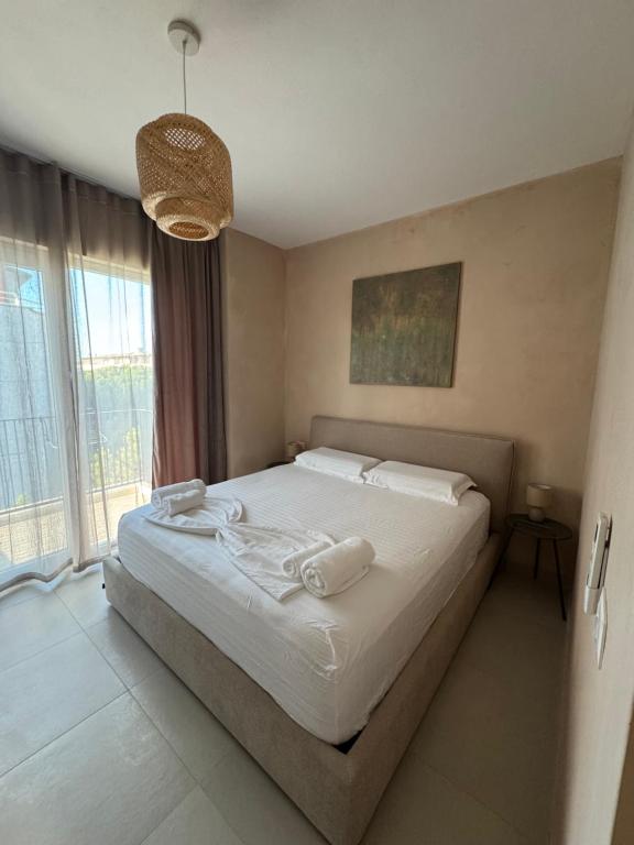 a bedroom with a bed with white sheets and a window at The Azure Breeze Beachfront Escape in Golem