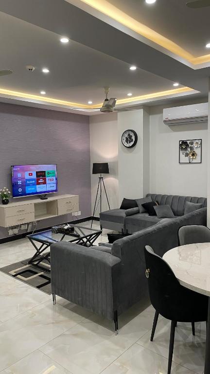 Una sala de estar con sofás y un televisor de pantalla plana. en Luxurious 2 bedroom apartment ISB, en Islamabad