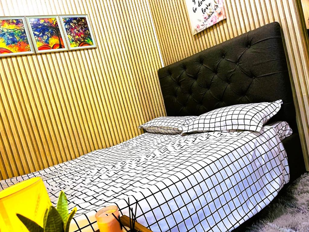a bedroom with a bed with a black headboard and pillows at Chateau Staycation in Manila