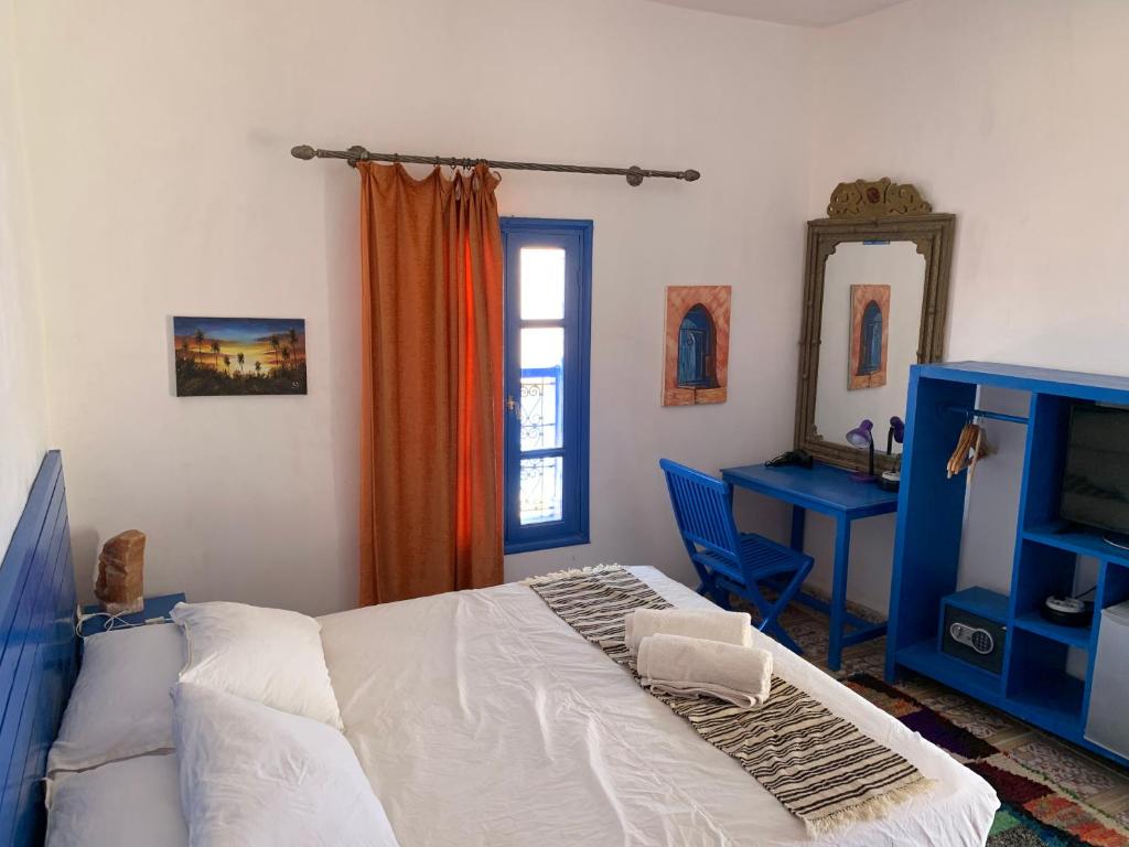 une chambre avec un lit, un bureau et un miroir dans l'établissement Chez Youssef, à Merzouga