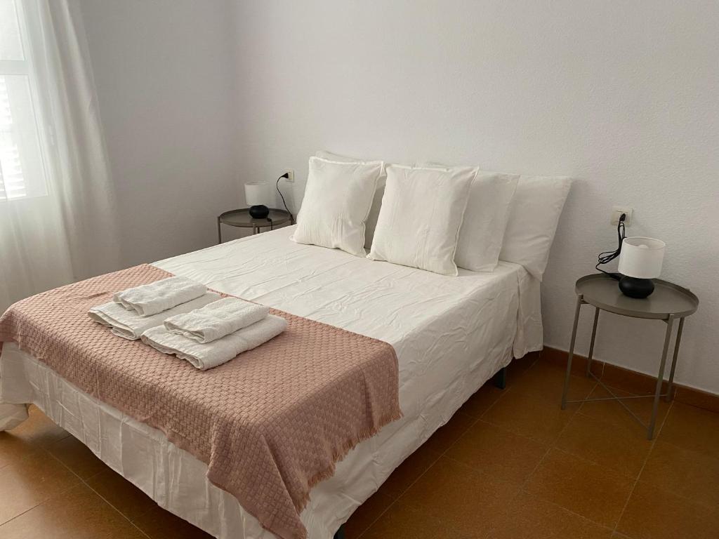 a bed with white pillows and two towels on it at BRISA del MAR in Isla Cristina