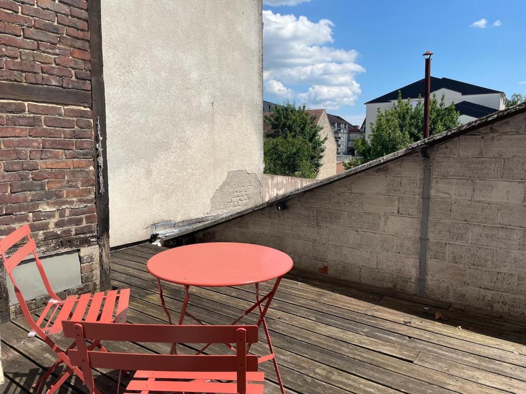a red table and two chairs on a balcony at Studio Cosy avec Terrasse - Gare a 2min & wifi in Compiègne