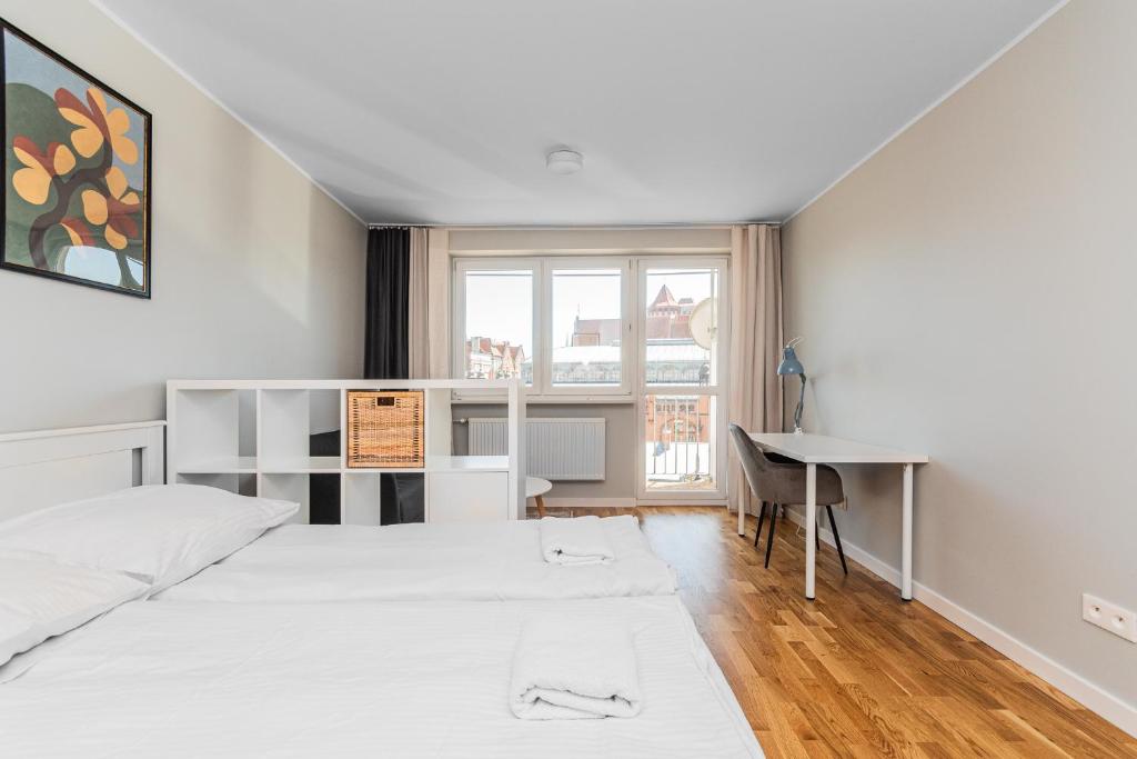 een slaapkamer met een bed, een bureau en een raam bij Frida by Grand Apartments in Gdańsk