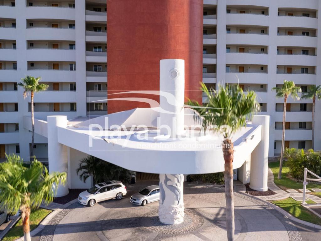 un bâtiment blanc avec des voitures garées devant dans l'établissement Playa Blanca Premier Unit 1104, à Isla Venado