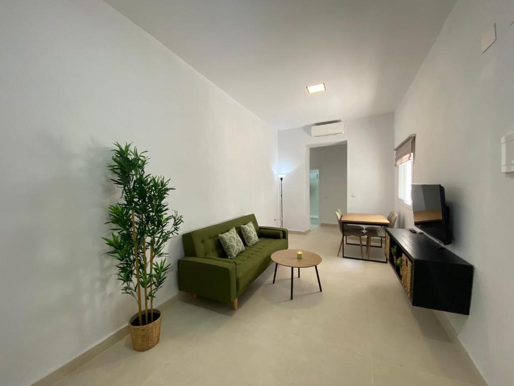 Una sala de estar con un sofá verde y una mesa. en Sol Sherry, en Jerez de la Frontera