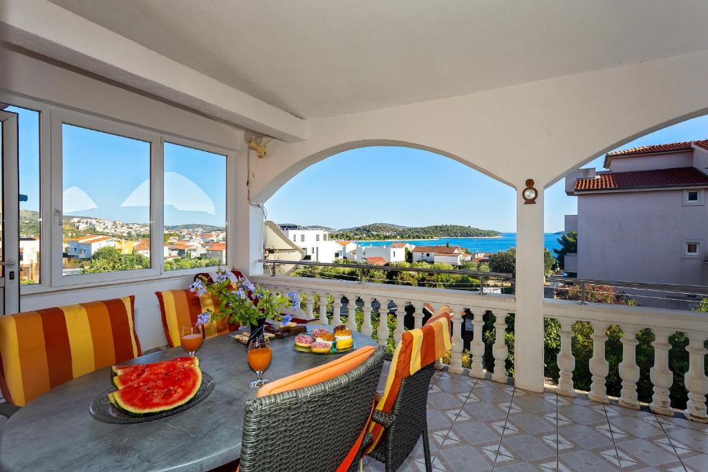 a balcony with a table and chairs with a view of the ocean at Spacious Terrace Apartments in Rogoznica