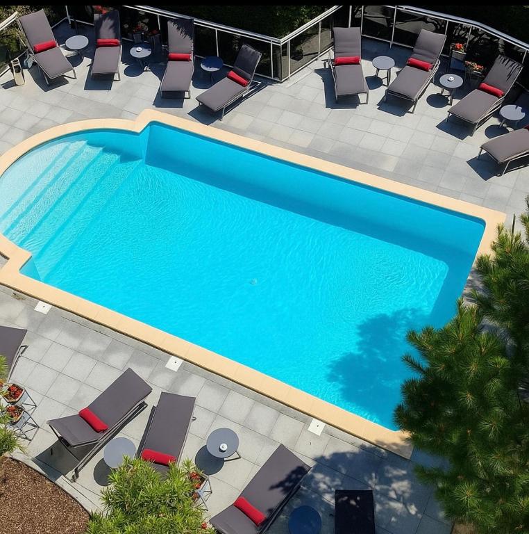 - une vue sur la piscine dotée de chaises longues et de chaises dans l'établissement Le M & Spa Bordeaux Aéroport by Hôtels & Préférence, à Mérignac