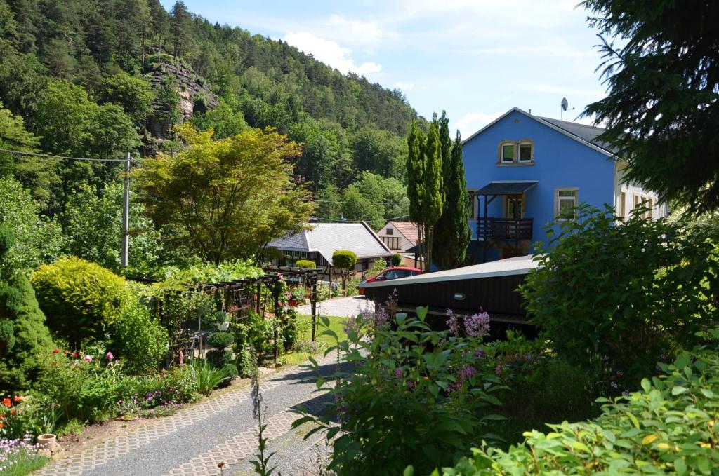 ein blaues Haus und ein Garten mit Blumen in der Unterkunft Sonnenhof Bad Schandau in Bad Schandau