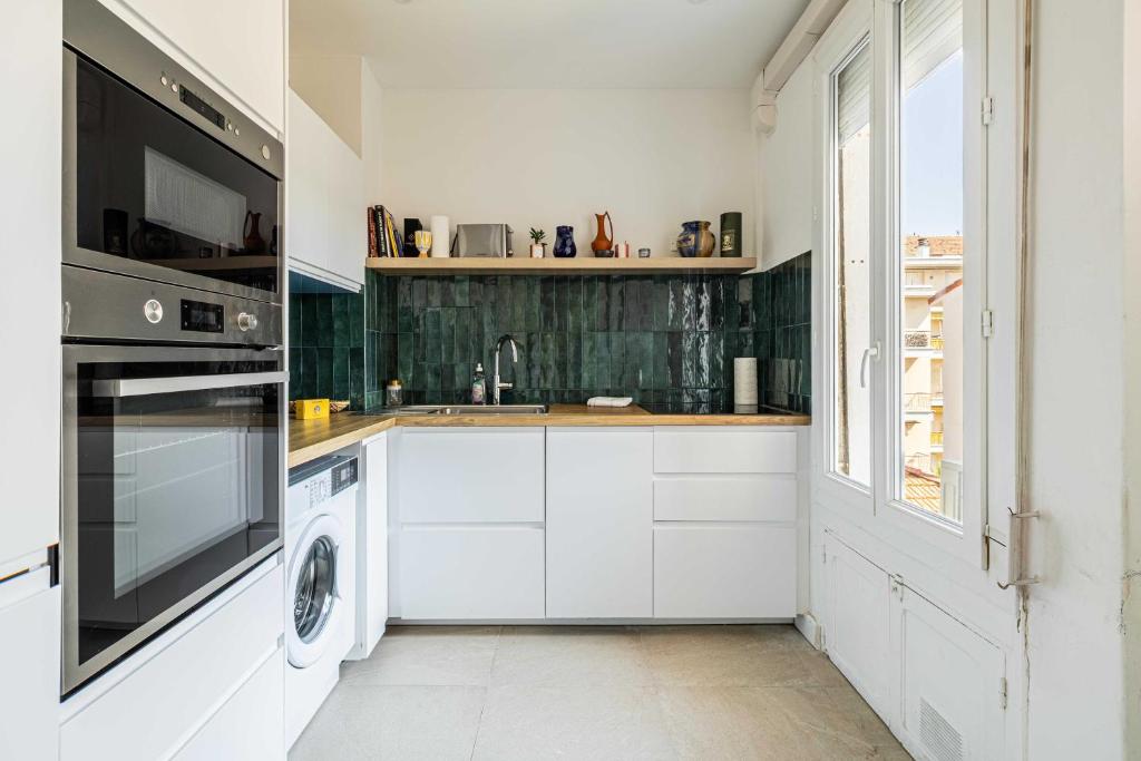 une cuisine avec des armoires blanches et une laveuse et une sécheuse dans l'établissement Elegance and Refinement, proximity to La Croisette, à Cannes