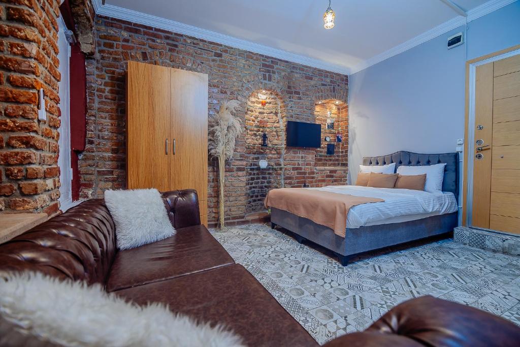 a bedroom with a couch and a bed and a brick wall at Taksim Nil Suite in Istanbul