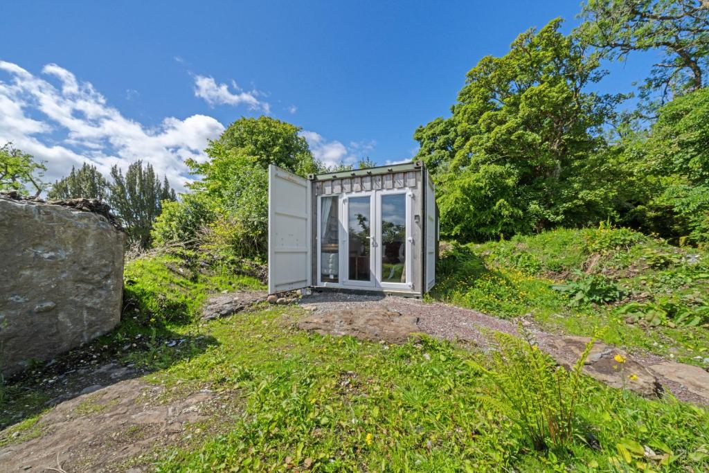 a small glass house on a hill with trees at Corry Lodge Estate - Sheperds Huts or Container Stays with Sea View in Broadford