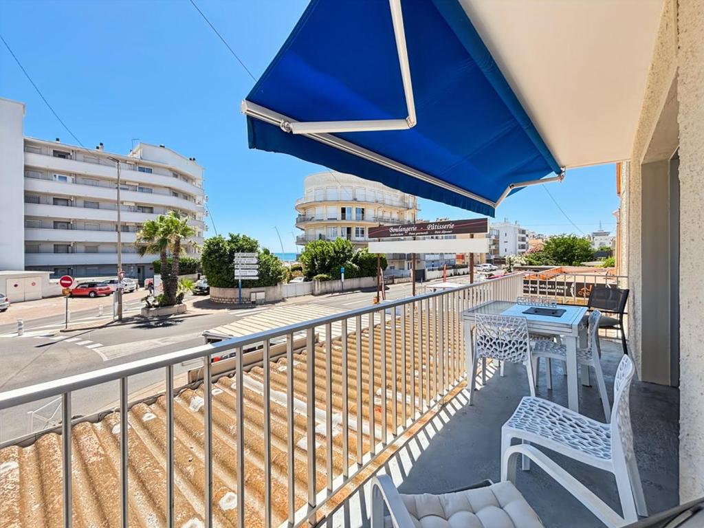 - un balcon avec un parasol bleu, une table et des chaises dans l'établissement Charmant T2 pour 4 pers à 150m plage, Palavas-les-Flots, proche centre - FR-1-559-3, à Palavas-les-Flots