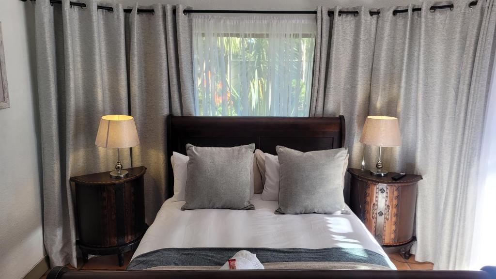 a bedroom with a bed with two lamps and a window at The Hops Inn in George