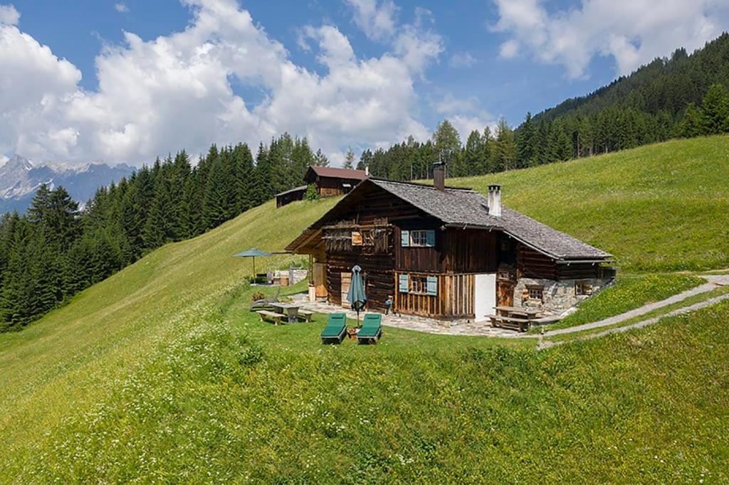 a log cabin on a hill with chairs in a field at Chalet Berghaus Bartholomäberg in Bartholomäberg