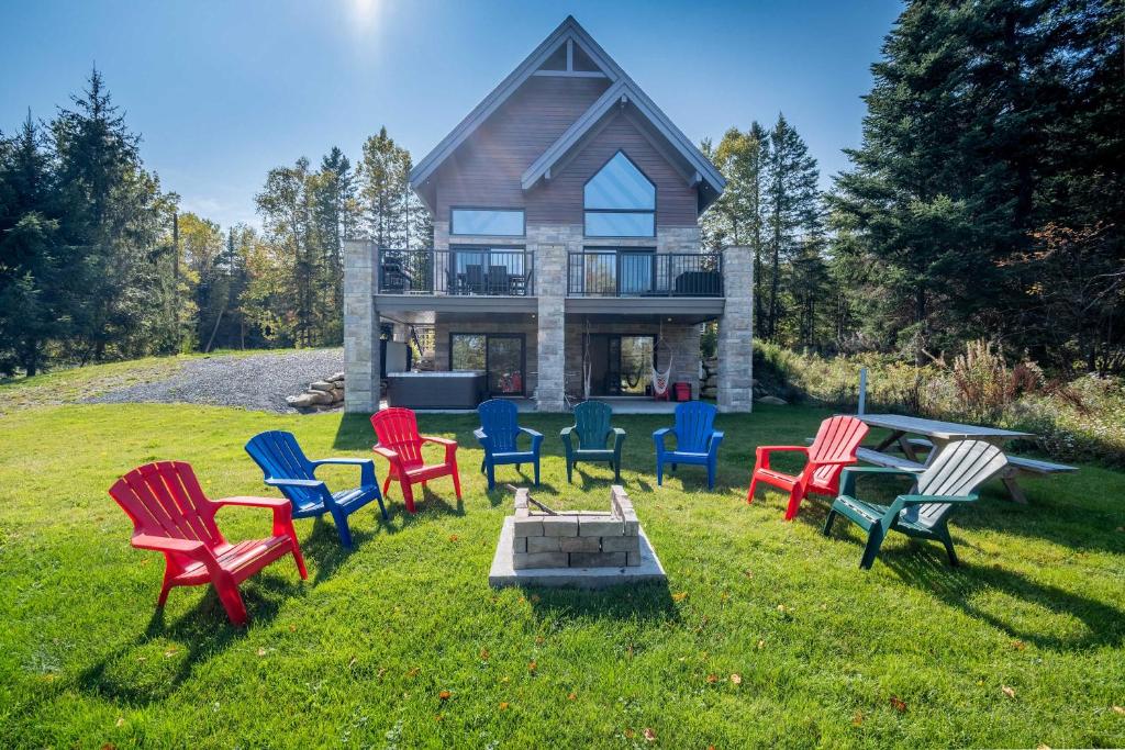 a group of colorful chairs in front of a house at Spa - Chalet la Barque du Bonheur in Sainte-Germaine-du-Lac-Etchemin