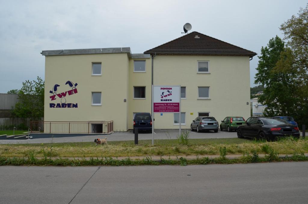 a large building with cars parked in a parking lot at Zwei Raben Pension in Mainz