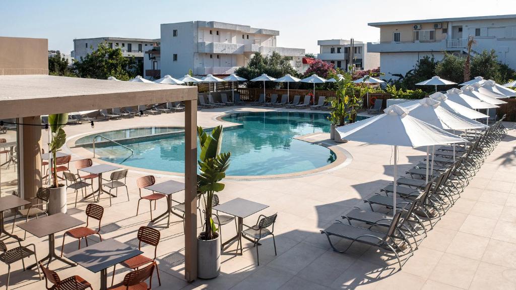 a swimming pool with chairs and umbrellas on a building at Time to Smile Saline in Tigaki