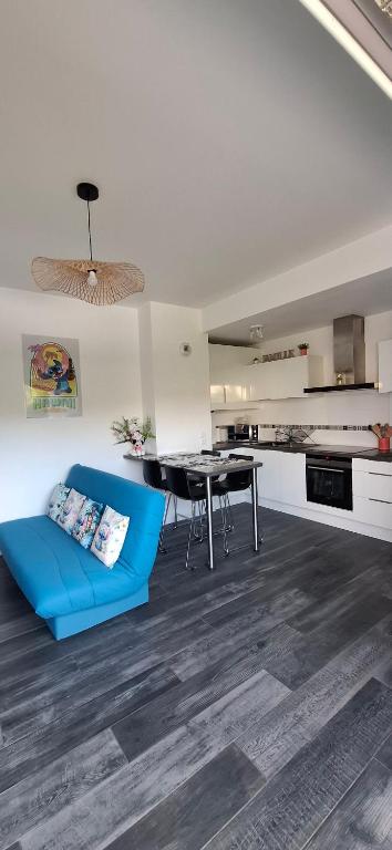 un salon avec un canapé bleu et une table dans l'établissement Appartement studio O fil de l'O à 12 kilomètres de Disneyland Paris, à Crécy-la-Chapelle