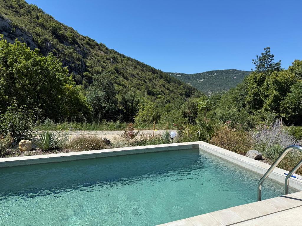 une piscine avec une montagne en arrière-plan dans l'établissement Gites Les Rochers de Plaisians, à Plaisians