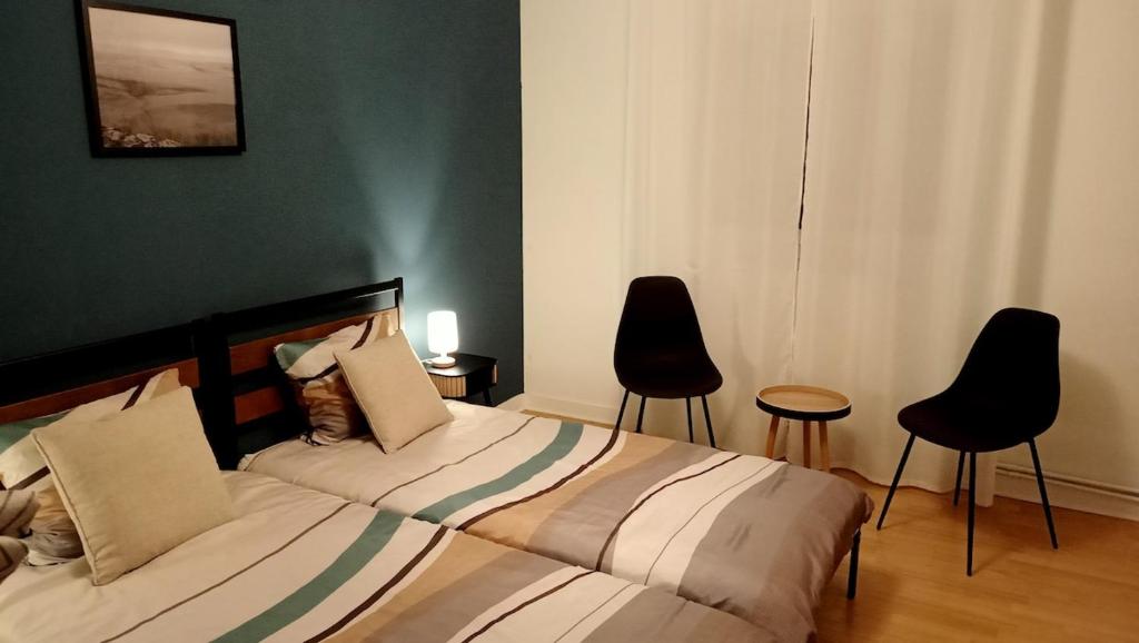 a bedroom with a bed and two chairs at Le Petit Mouton in Pontorson