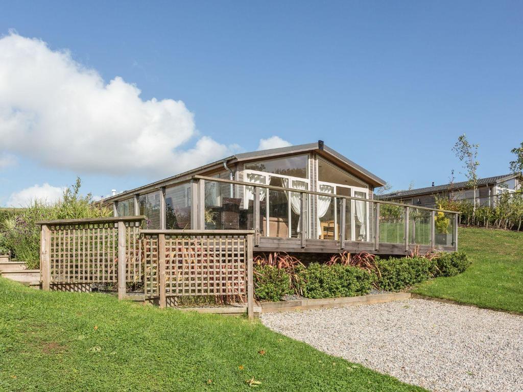 a house with glass windows and a fence at 2 Tree Tops in Looe