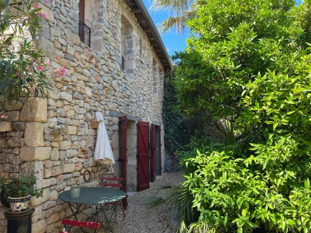 a stone building with a door and a table and a umbrella at Chambres d'hotes lecortile in Villeneuve-lès-Maguelonne