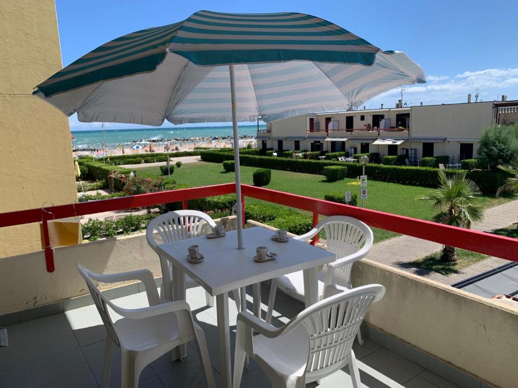 a table and chairs with an umbrella on a balcony at Appartamento La Jolla Fano in Fano