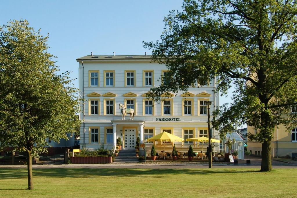 un bâtiment blanc avec des tables devant lui dans l'établissement Parkhotel del Mar, à Sassnitz