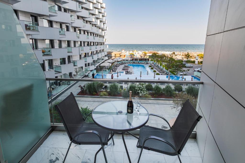 a glass table and chairs on a balcony with a view of the beach at One SeaView std in Infinity Pool & Spa Resort in Mamaia Sat/Năvodari