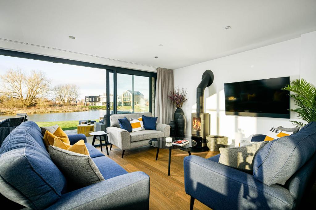 a living room with blue furniture and a large window at Minety Lake 72 ML72 Lower Mill Estate Cotswolds in Somerford Keynes