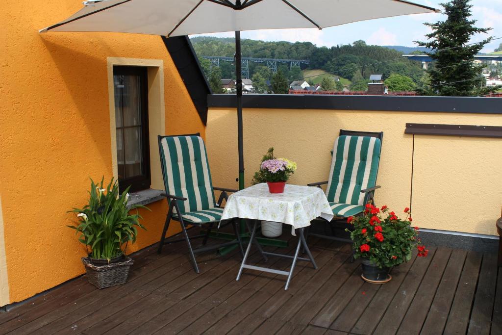 ein Tisch mit zwei Stühlen und einem Sonnenschirm auf einem Deck in der Unterkunft Ferienwohnung Edelweiß im Erzgebirge in Markersbach