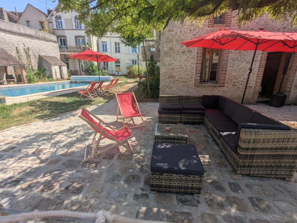 a patio with a couch and chairs and an umbrella at Poule Noire Ukraine in Égreville