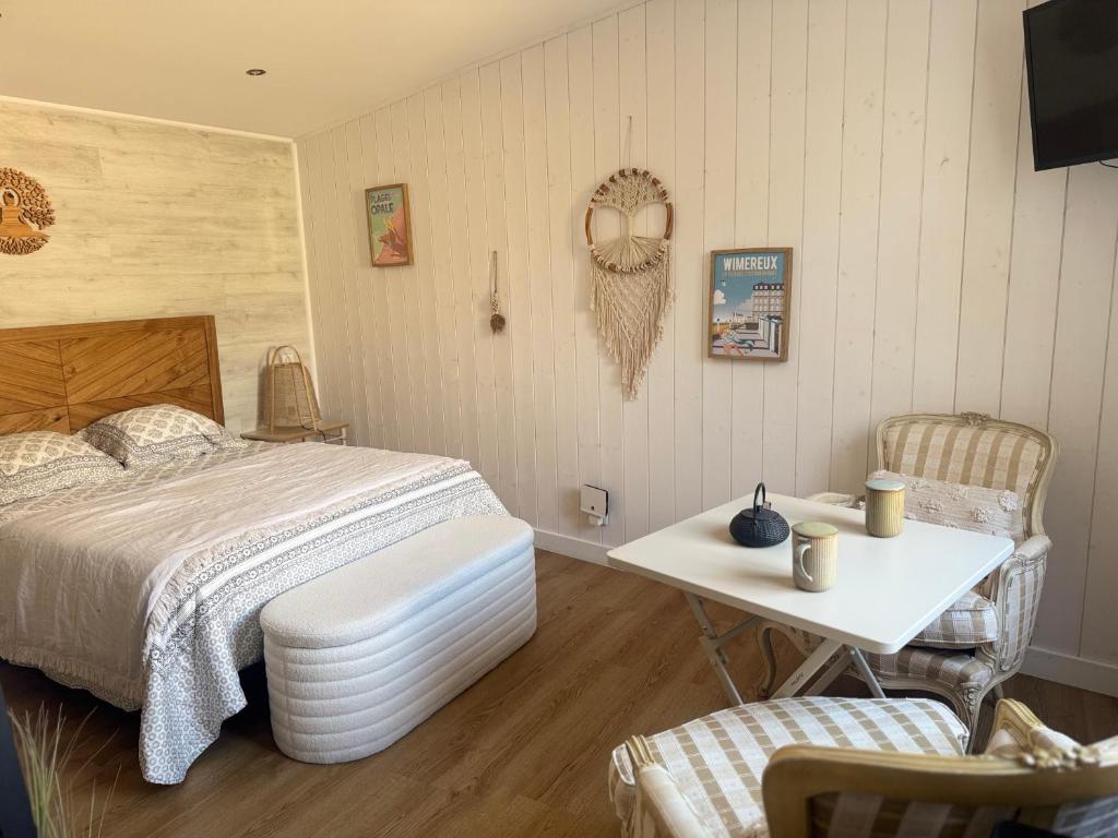 une chambre avec un lit, une table et des chaises dans l'établissement Wimdream , havre de paix cosy, à deux pas de la mer et du centre ville, à Wimereux