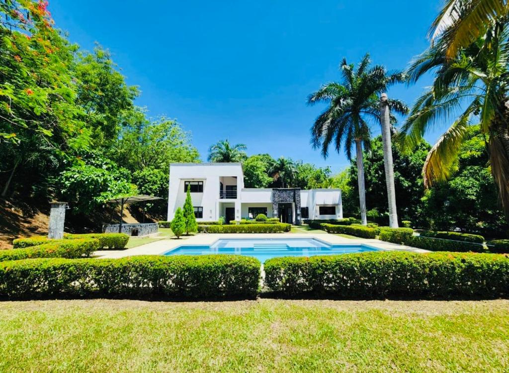 a house with a swimming pool in front of a yard at Casa de campo in Santa Fe de Antioquia