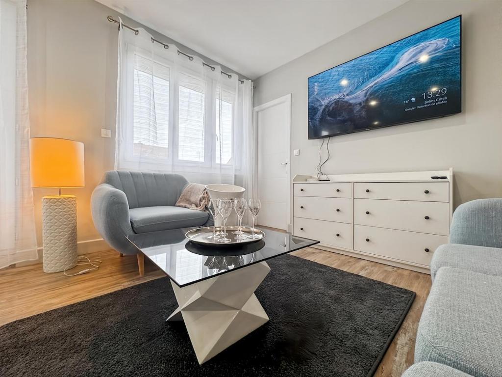 una sala de estar con un sofá y una mesa en L'art de vivre en Baie, bel apt avec parking, en Saint-Valery-sur-Somme