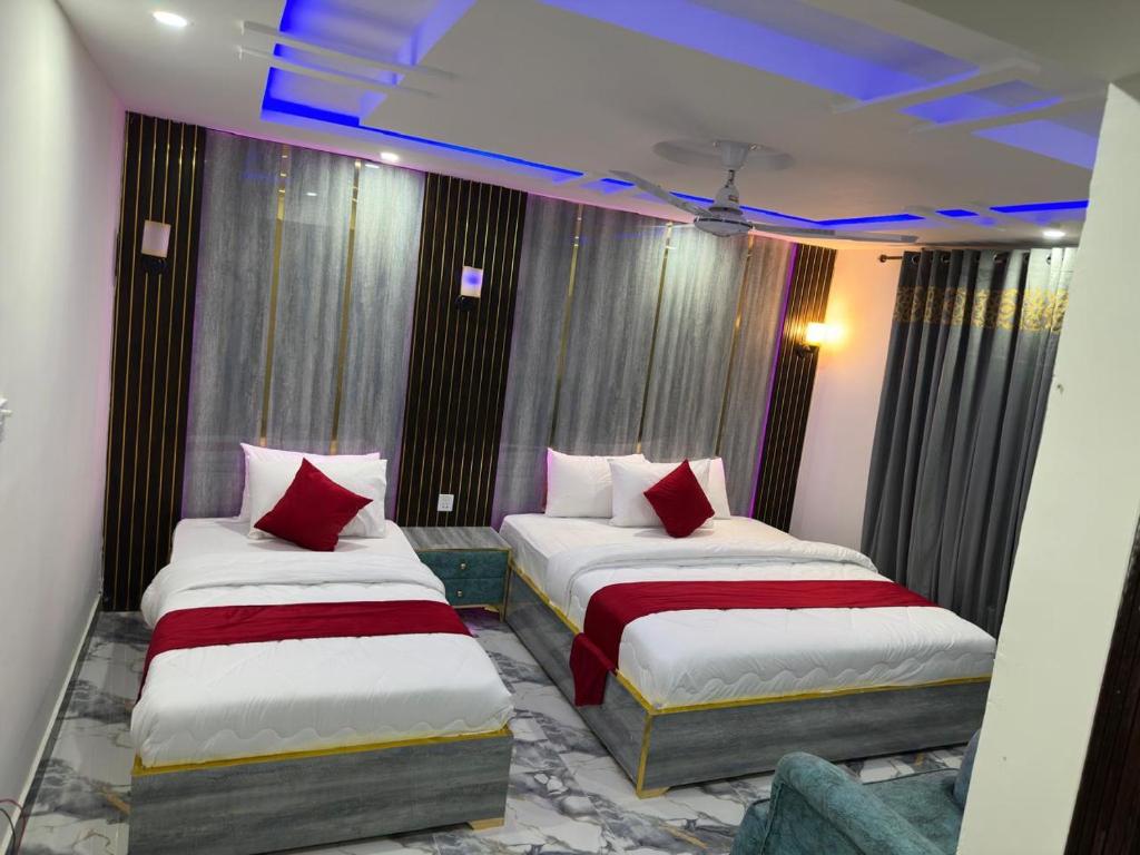 two beds in a hotel room with red pillows at Decent Luxury Hotel Hunza in Alīābād