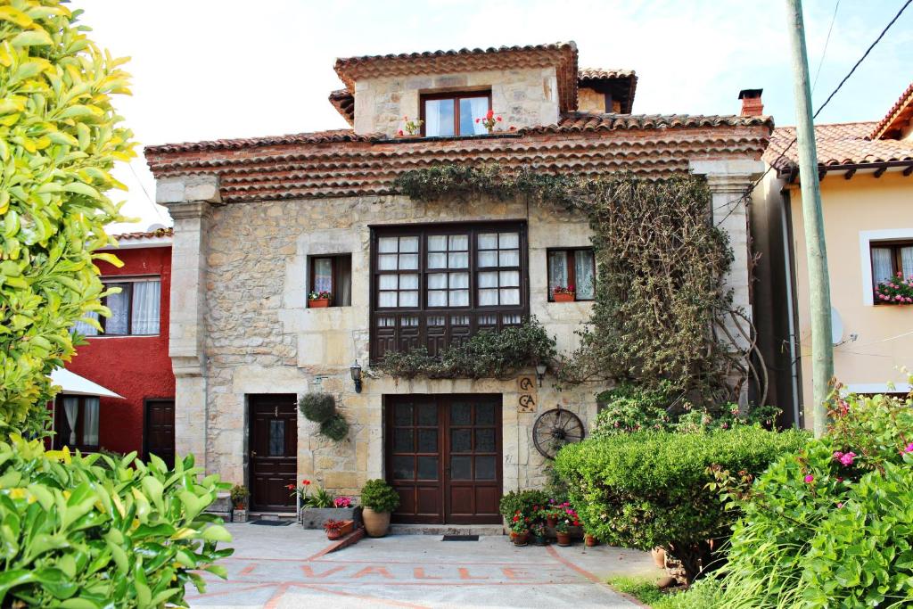 una antigua casa de piedra con ventanas y plantas en Casa de Aldea El Valle, en Buelna