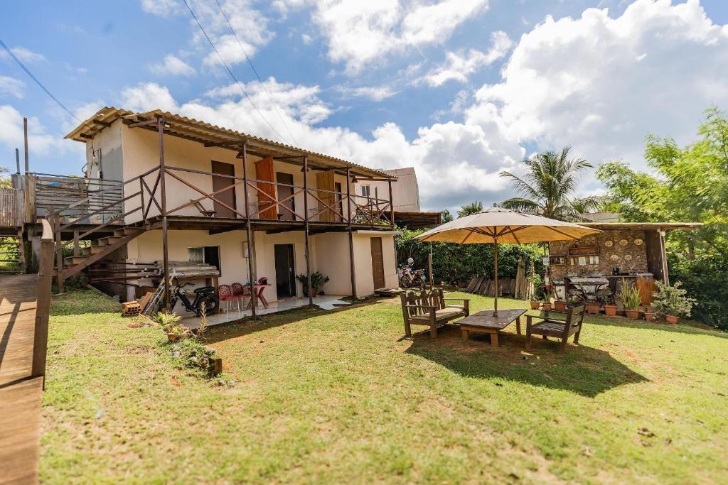 una casa con una mesa y una sombrilla en el patio en Casa do Calico em Fernando de Noronha!, en Fernando de Noronha