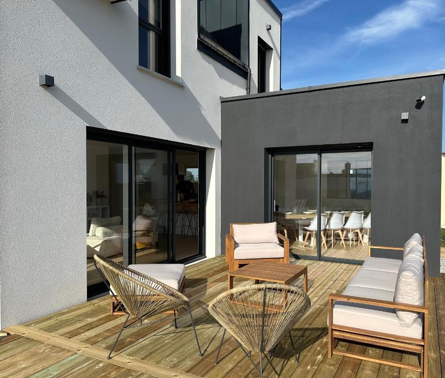 a patio with chairs and tables on a building at Maison neuve proche des plages in Plouarzel