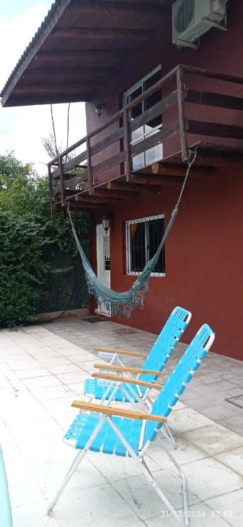 two blue chairs and a hammock in front of a house at Entrepinos I in Juana Koslay 