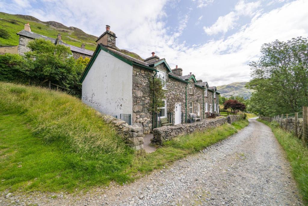 a row of stone houses on a dirt road at 4 Low Rake - Former Miners Cottage in Glenridding