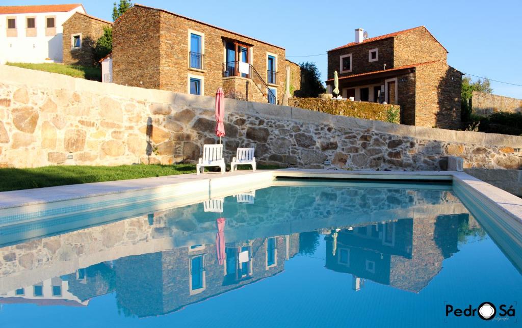 una piscina con 2 sillas y una casa en Caramulo - Casas do Espigueiro, en Macieira de Alcoba
