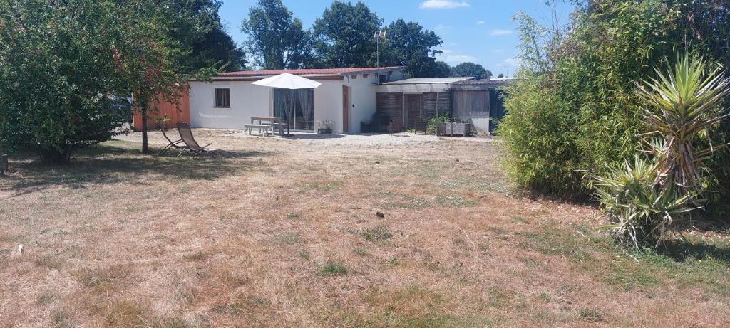 a house with a table and an umbrella in a yard at Le Petit Gîte in Les Essarts