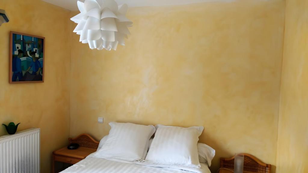 a bedroom with a bed with white pillows and a chandelier at Au Cœur De La Riviera Des Alpes T2 in Brison-Saint-Innocent