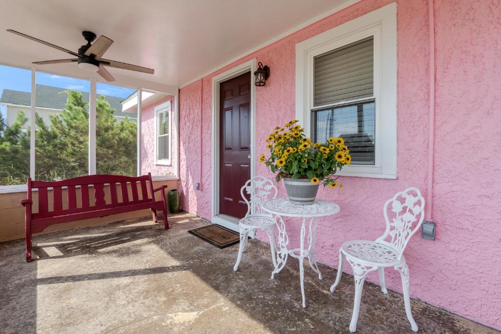 a pink house with a table and chairs and a window at The Pink House in Kill Devil Hills