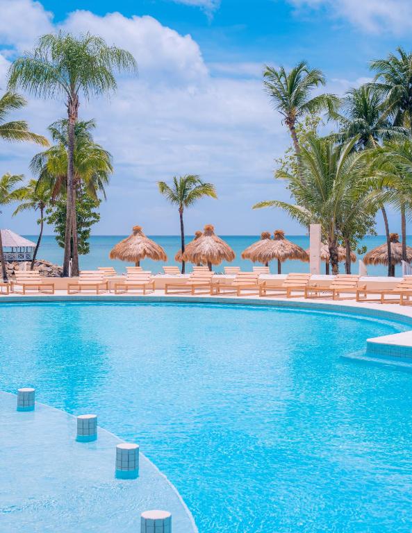 una piscina con palme e ombrelloni di Secrets Saint Lucia Resort & Spa - All Inclusive a Gros Islet