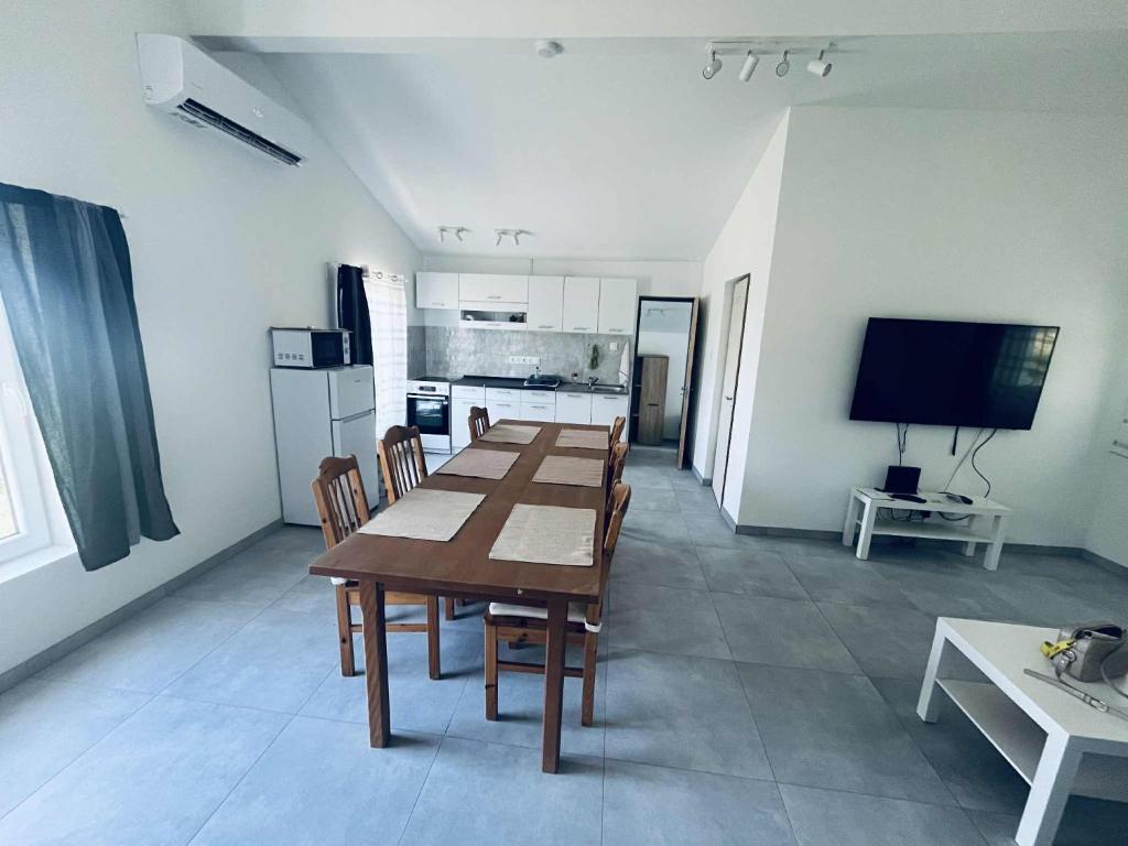 a dining room with a table and a kitchen at Gádé Apartmanház in Sukoró